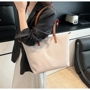 Detail of cream nylon tote bag with tan leather straps and silver metal hardware