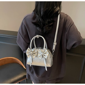 Détail d'un sac à bandoulière argenté métallisé avec des nœuds décoratifs élégants