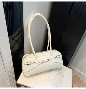 Detailed close-up of a minimalist cream shoulder bag featuring elegant silver metal buckles