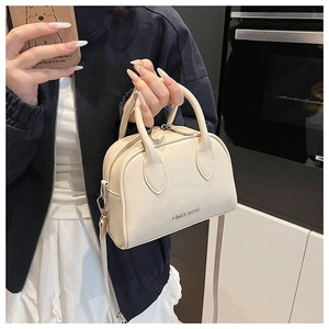 Detailed close-up of cream white Boston bag featuring lychee grain leather and metal logo