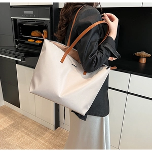 Close-up of minimalist large nylon tote bag with brown handles and metal logo detail
