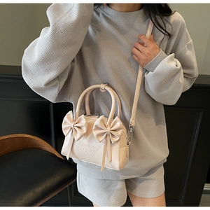 Mannequin portant un sac Boston rose avec nœuds, détails métalliques et fermeture éclair