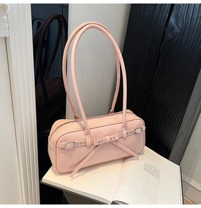 Detail of pink PU leather underarm bag featuring long ribbon bow and silver rivets