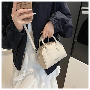 Detail view of cream lychee texture mini Boston bag with top handles and silver logo