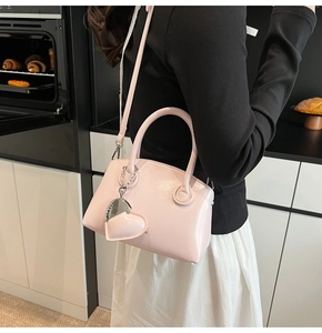 Close-up of pink glossy bowling bag with heart charm and detachable shoulder strap