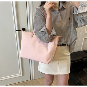 Detailed view of pink nylon tote bag being worn by a model in a casual lifestyle setting