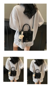 Detail view of black PU bucket bag with golden brand logo and cute brown bear charm