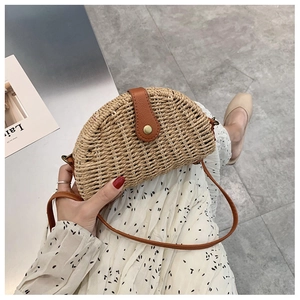 Detail of a half-moon straw bag featuring brown leather flap and vintage gold buckle