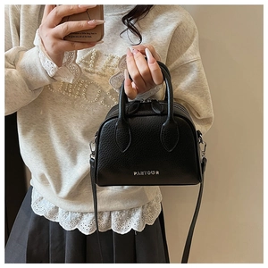 Detail of black lychee grain leather boston bag with silver logo and adjustable shoulder strap