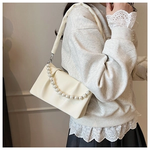 Détail du sac bandoulière plissé crème avec chaîne décorative à grosses perles