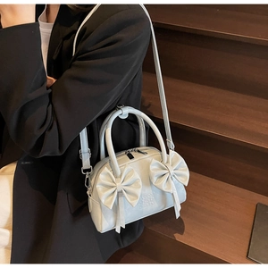 Détail du sac Boston bleu avec nœuds papillon montrant le grain du cuir