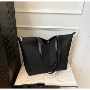 Detailed view of black nylon tote bag with durable silver zipper closure and slim handles