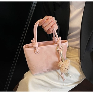 Detail of pink bucket bag with plush bear charm and MIKAXIQI & BAG printed text