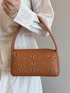 Brown leather underarm bag with silver grommets and adjustable shoulder strap for women