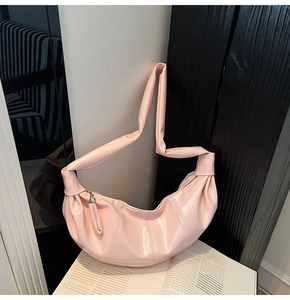Detail of light pink crescent moon bag showing pleated texture and smooth vegan leather finish