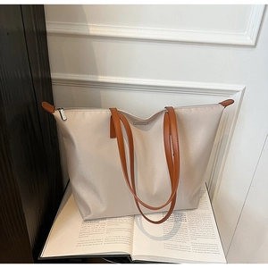 Detailed close-up of a nylon tote bag with leather handles on a magazine background