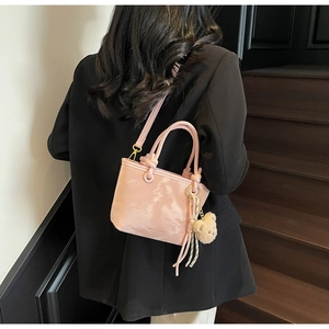 Detail showing pink bucket bag with marble texture and plush bear charm on black blazer