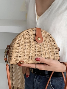 Handwoven semicircular straw crossbody bag with brown leather trim and metal snap closure