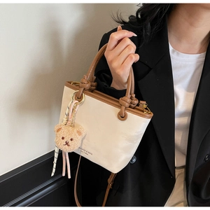 Detail of Korean style bucket bag with brown handles and a cute plush bear pendant