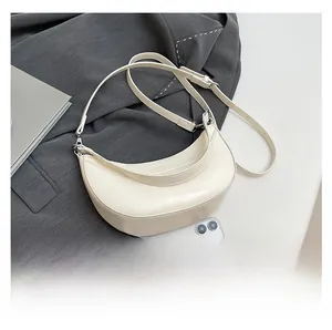 Détail d'un sac croissant crème en cuir huilé avec bandoulière réglable et téléphone