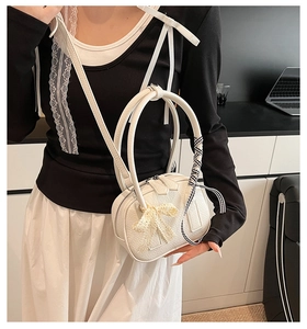 Close-up of a white textured bowling bag featuring a lace bow and plaid ribbon detail