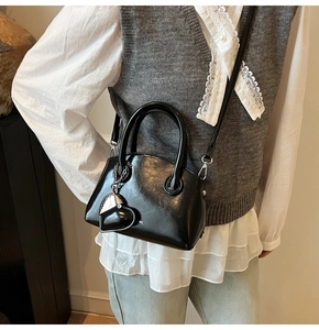 Detail of black leather handbag with chic heart charm and elegant shoulder strap styling