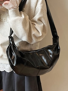Minimalist black glossy croissant shoulder bag with knotted strap and crescent shape