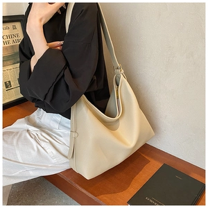 Detail of a large beige leather tote bag with pebble texture and side buckle detail