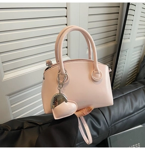 Close-up of pink shell-shaped PU leather handbag with heart charm and brand logo