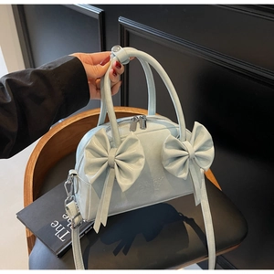 Détail du sac à main bleu clair avec nœuds et logo gaufré sur un siège en cuir