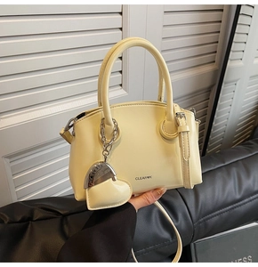 Close-up of cream leather mini handbag with top handle and heart-shaped charm detail