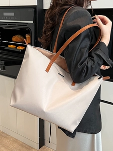 Minimalist beige nylon tote bag with brown leather straps shown on a female shoulder