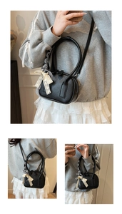 Detail of black pebbled leather bowling bag with round handles and lace bow charm