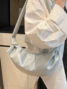 Minimalist light blue faux leather crescent bag with pleated texture and shoulder strap