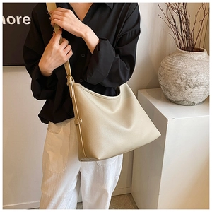Detail of minimalist beige hobo bag showing litchi grain texture and wide shoulder strap