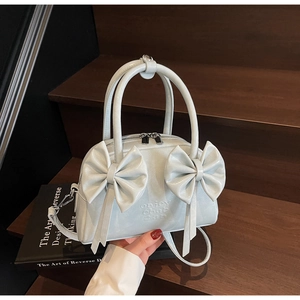 Détail du sac à main bleu clair avec nœud, fini nacré et doubles poignées