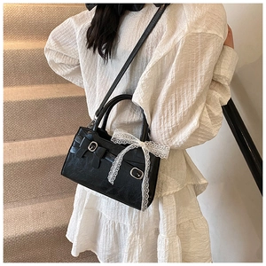 Donna elegante con borsa in pelle nera e nastro di pizzo su una scala con moquette