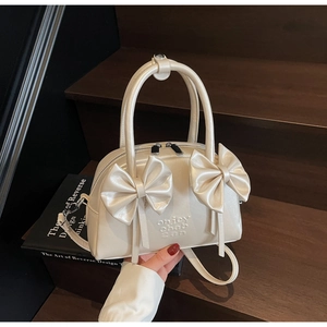 Détail du sac Boston en cuir blanc crème avec grands nœuds et lettrage embossé