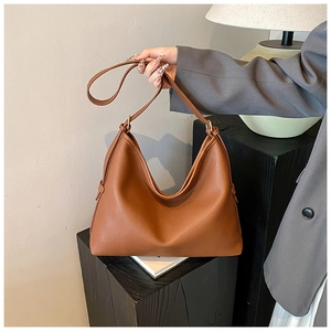 Detail of minimalist brown leather tote bag with lychee texture and gold metal buckle