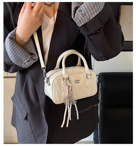 Chic quilted boston bag with tennis racket charm and metal logo on a crossbody model