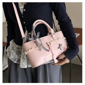 Close-up of pink PU leather handbag featuring lace trim and a plaid bow decoration