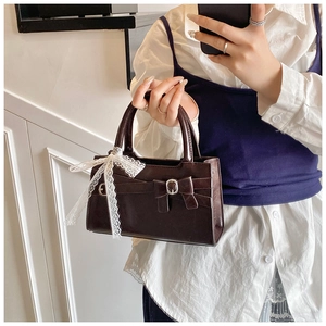 Dettaglio della borsa vintage marrone cioccolato con fiocco e nastro in pizzo bianco