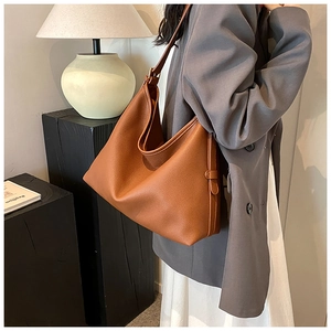Brown lychee leather tote bag shown on shoulder, highlighting its large capacity and drape