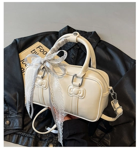Detail of creamy white Boston bag featuring 3D bow relief and delicate lace ribbons