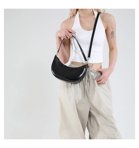Détail du sac demi-lune en cuir noir avec boucles métalliques sur un mannequin