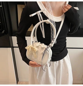 Close-up of white lychee textured bag featuring lace bows and checkered ribbon details