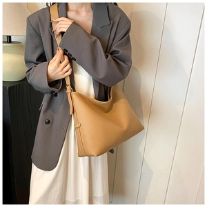 Close-up of light brown lychee grain leather tote bag with adjustable metal buckle strap