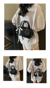 Detail of black glossy faux leather handbag with lace ribbon and silk wrapped handle