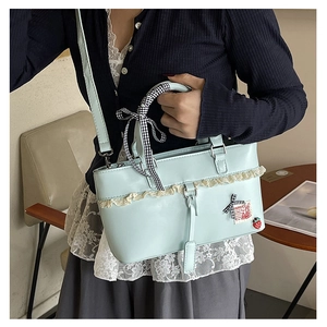 Detail of mint green shoulder bag with lace trim and black and white checkered bow