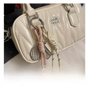 Detail of cream white quilted handbag featuring silver logo and creative metal charms